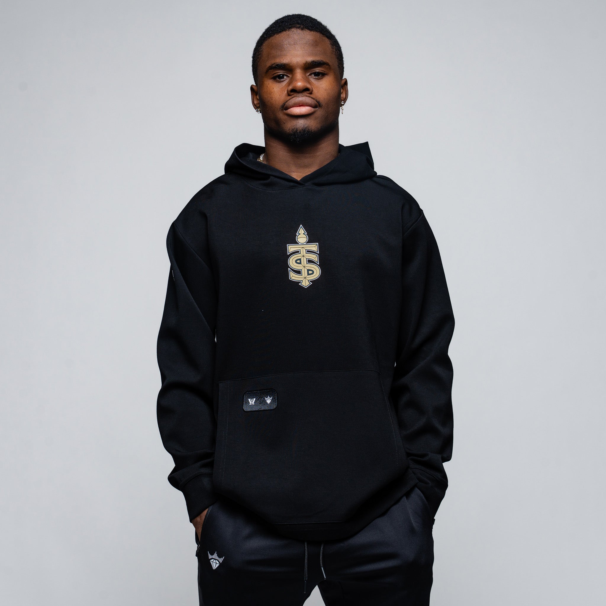 Person wearing a black hoodie with a logo on a gray background