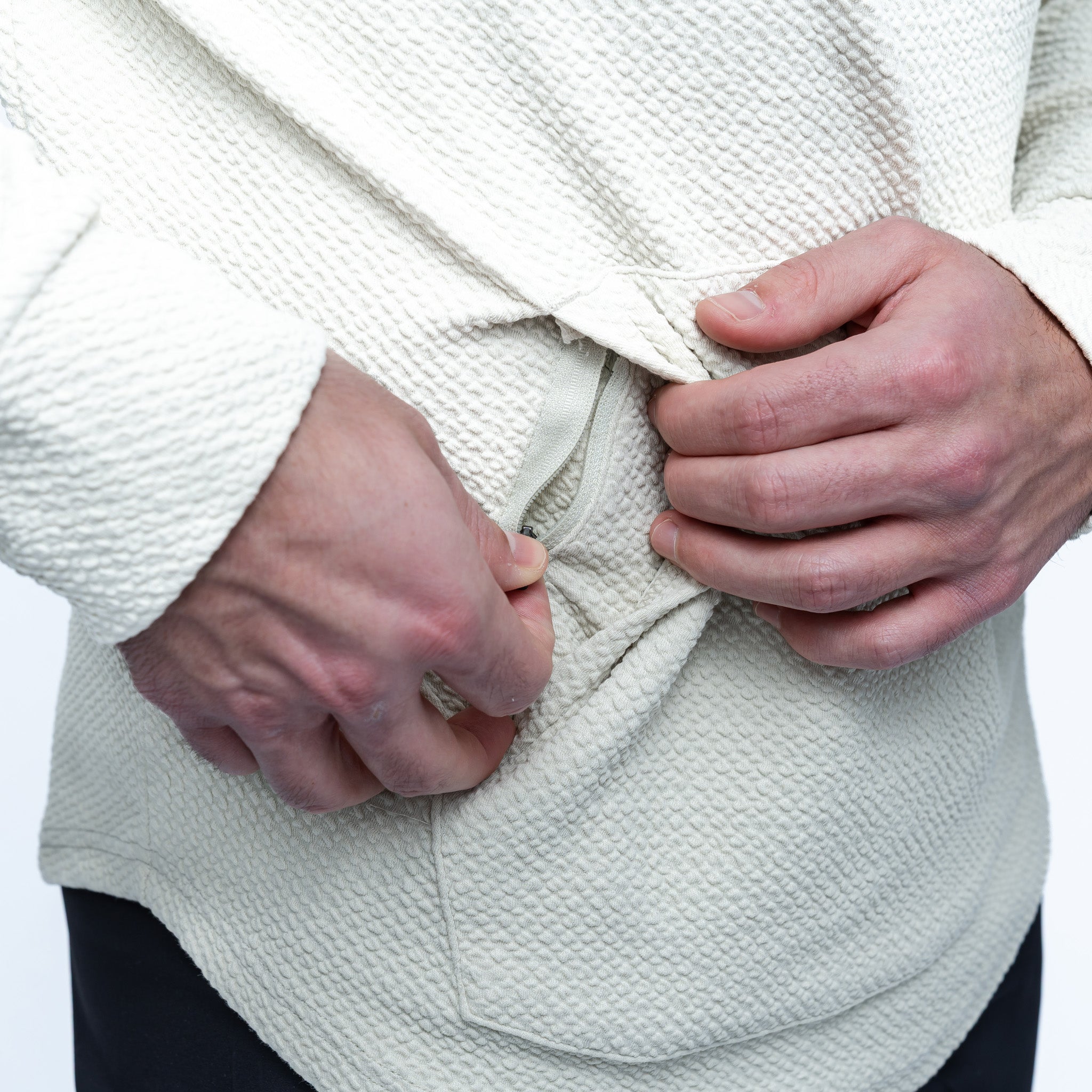 Person tying a white robe with a close-up of hands on a plain background