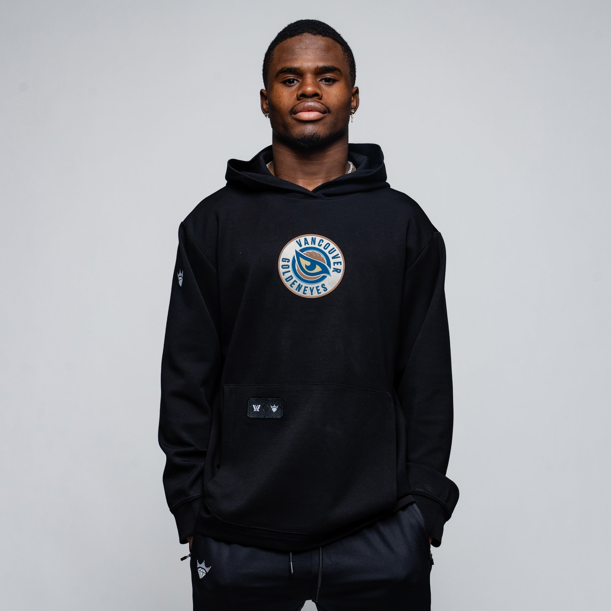 Person wearing a black hoodie with a logo on a gray background