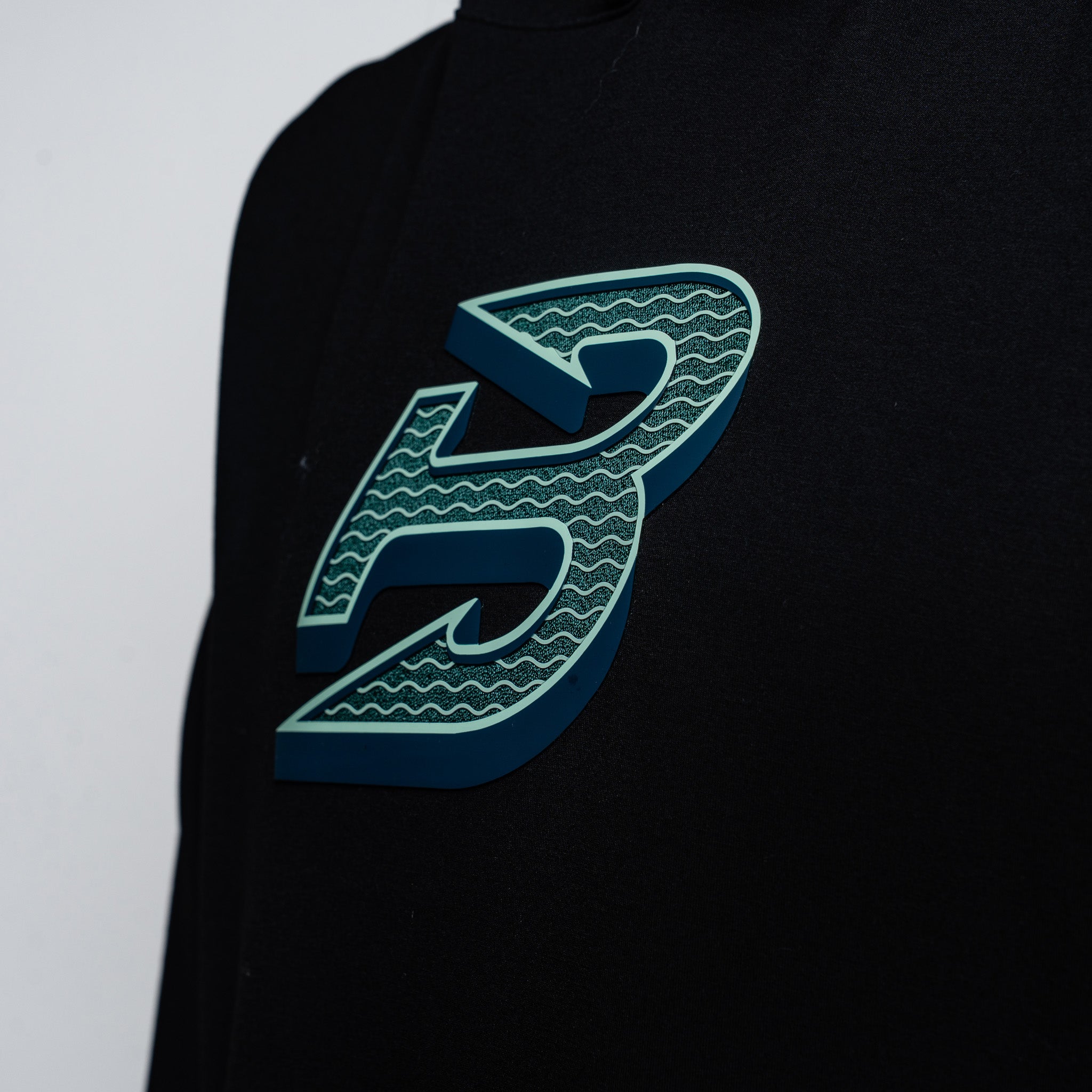 Black shirt with a green logo on a light gray background