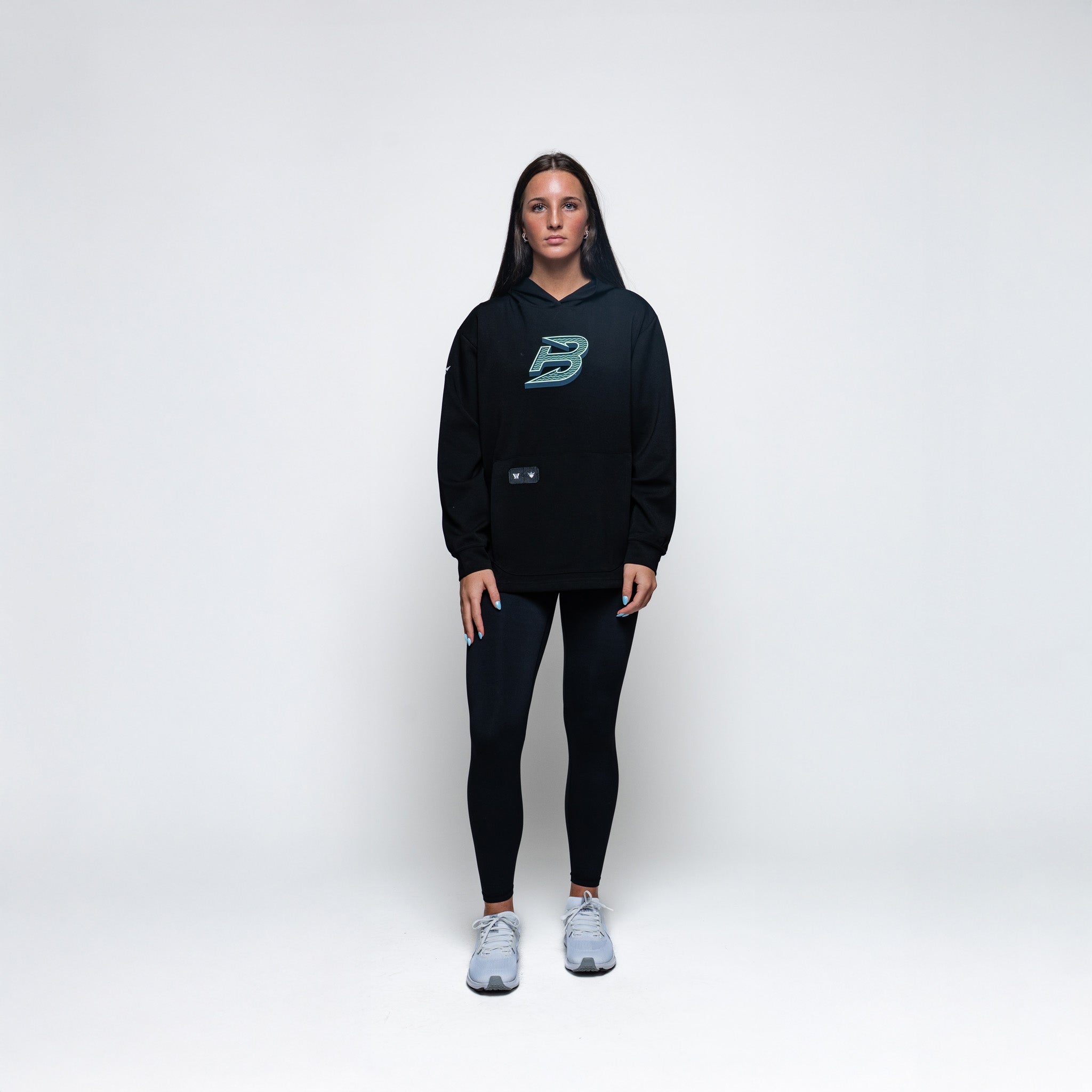 Person wearing a black hoodie and leggings with a logo on a white background